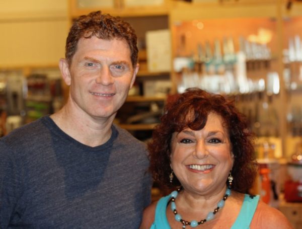 Red haired man in dark t-shirt on left with his arm around dark haired woman in turquoise top.