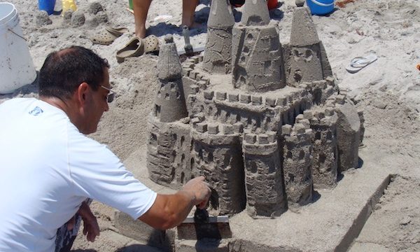 A man finishing his sand castle on the beach