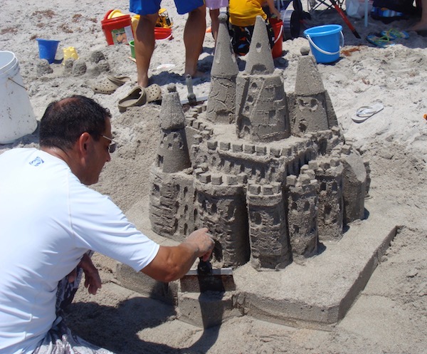A man finishing his sand castle on the beach