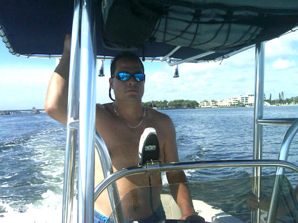 A dark haired man with sunglasses stealing a speedboat