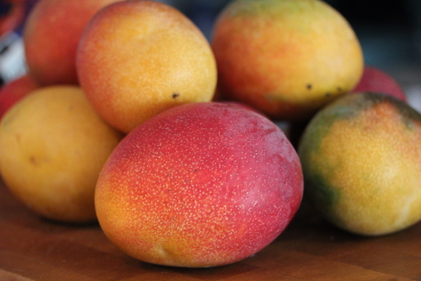 A whole mess of ripe mangoes on a butcher block
