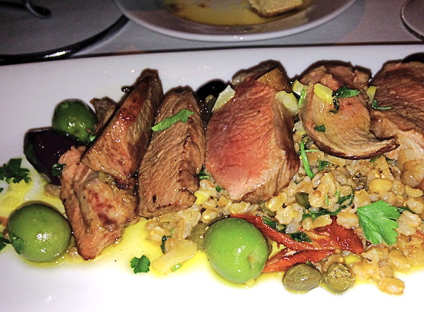 A large white oval plate covered with New Mexican Lamb with Faro and Olives