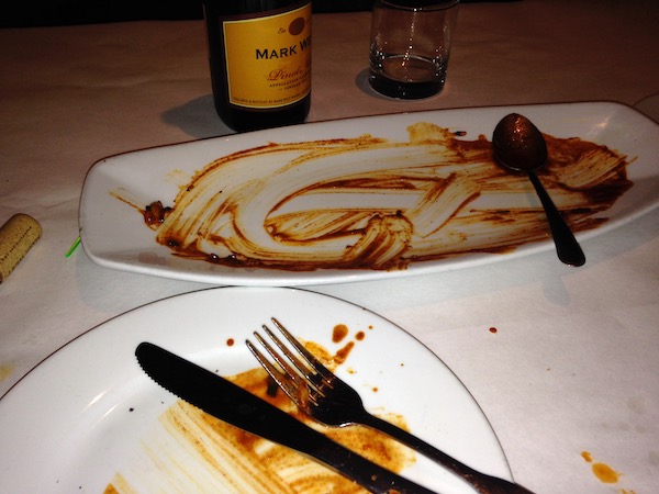 Two white plates with the bare remains of some red sauce.