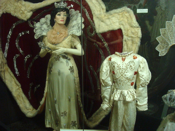 Female mannequin in white gown with flowers and a child's costume to the right