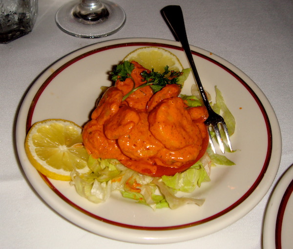 Cream colored plate with dark red border holding Shrimp with Remoulade Sauce on bed of lettuce with lemon slices