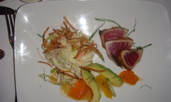 Square white plate with three slices of Seared and Chilled Yellowfin Tuna with Avocado, Wasabi Slaw, Soy-Ponzu Sauce and Sesame Wontons