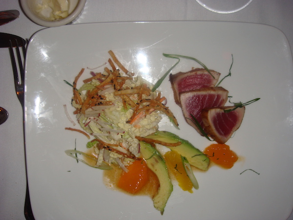 Square white plate with three slices of Seared and Chilled Yellowfin Tuna with Avocado, Wasabi Slaw, Soy-Ponzu Sauce and Sesame Wontons