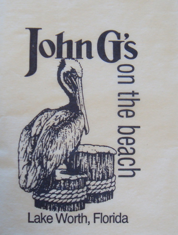 Gray menu cover with a pelican sitting on a wood piling and John G's across top on the beach vertically on right