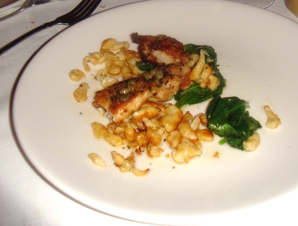 A white plate topped with Paneed Mississippi Rabbit, Lemon-Caper Brown Butter, Wilted Spinach, Spaetzle