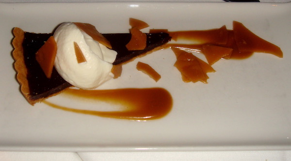 A white plate topped with Toffee-Chocolate Tart Brown Butter Shortbread Crust and Coconut Cream