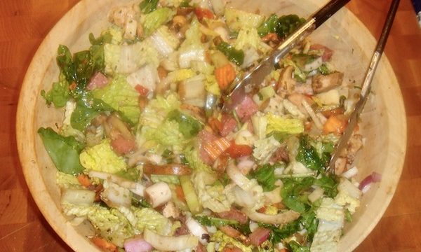 Light colored wood salad bowl containing a huge antipasto dinner salad