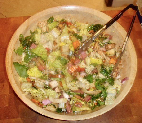 Light colored wood salad bowl containing a huge antipasto dinner salad