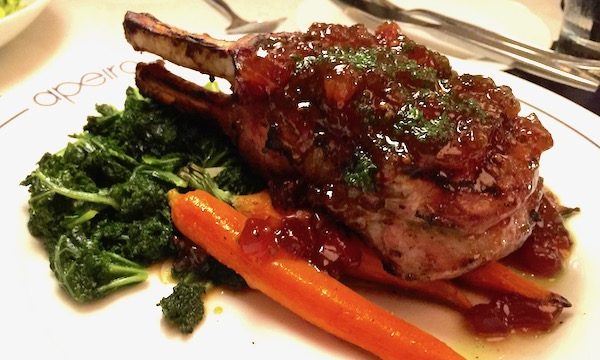 A white plate topped with 14 oz. Double Pork Chop at Apeiro Kitchen and Bar