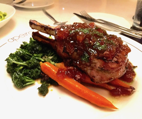 A white plate topped with 14 oz. Double Pork Chop at Apeiro Kitchen and Bar