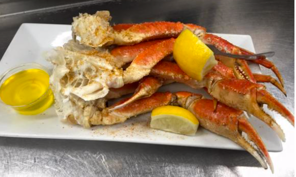 A white rectangular plate topped with crab legs and lemon wedges