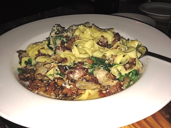 A large white pasta dish filled with Pappardelle with guanciale, Mepkin Abbey mushrooms, arugula, parmesan