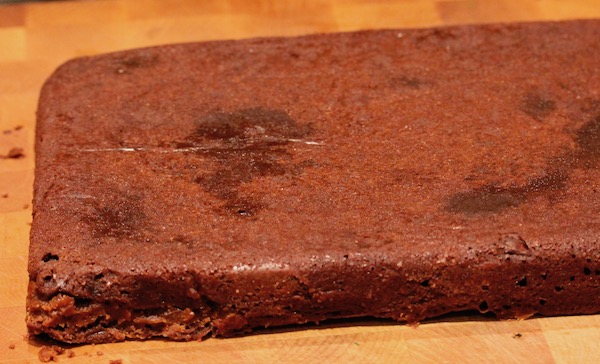 A sheet of baked brownies uncut on a butcher block.