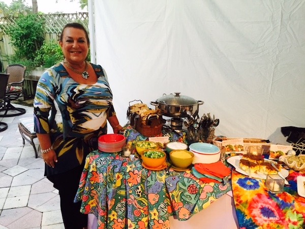 A woman standing in front of a colorful buffet table with lots of food.