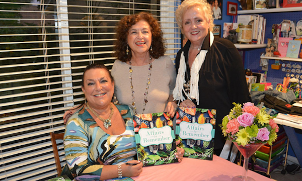 Three woman, one seated and two holding books