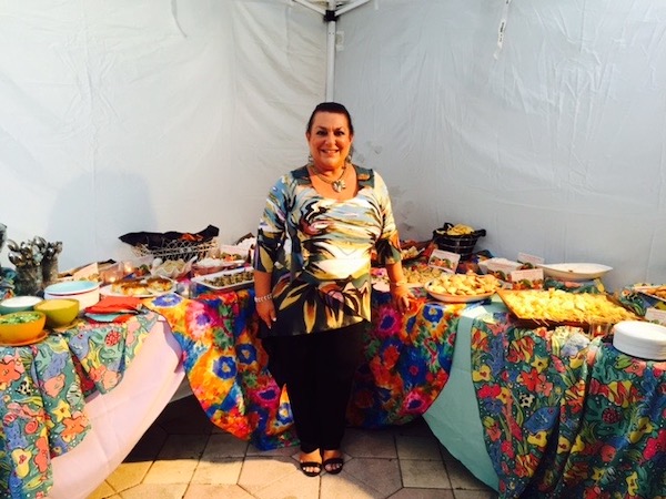 A woman standing in front of a colorful buffet table with lots of food.