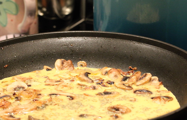 An anodized pan filled with cooked eggs and onions