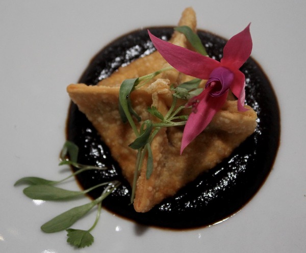 A large white plate filled with Buñelo + Duck Confit + Mole Negro