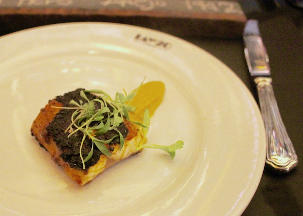 A pale yellow plate topped with Branzino + Tallo Sauce + Plantain Purée