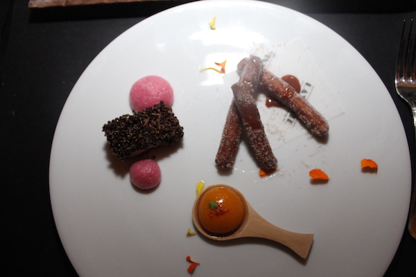 A white plate topped with pink, orange and brown ice cream balls and cookies