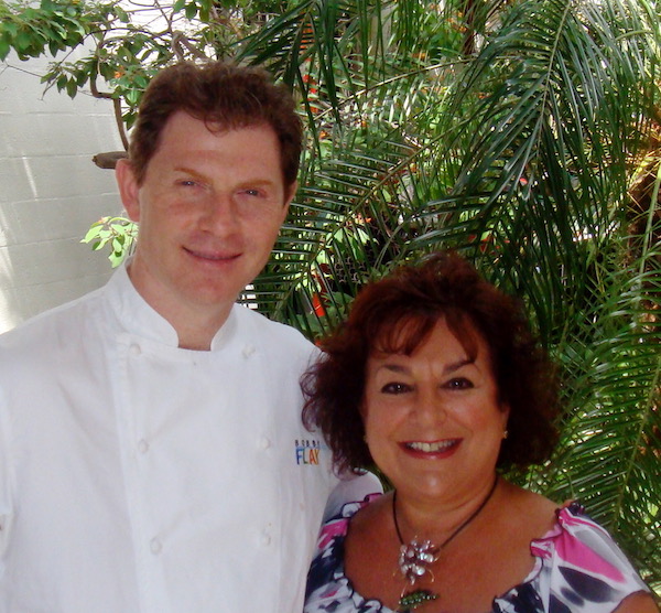 A man in a chef coat with his arm around a woman in a pink, black and white top.