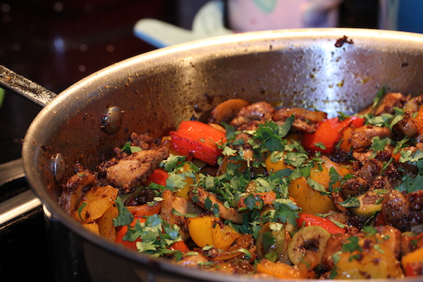 A steel sauté pan filled with Chorizo Spiced Chicken Thighs with Peppers Onions Olives and Mushrooms