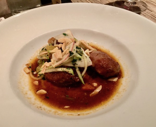 Pork Cheek Country Captain with Raisins, Turnips and Almonds with jus in a white shallow bowl