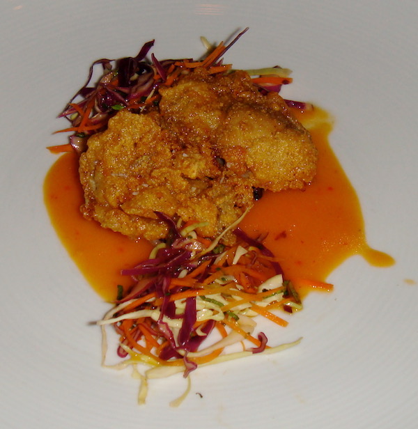 A white plate topped with fried oysters, slaw and a deep orange sauce