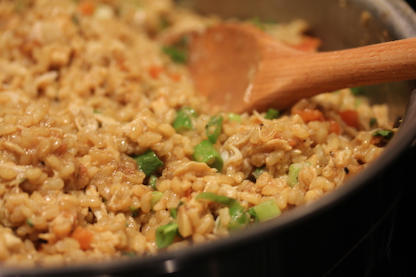 Anodized sauté pan filled with rice, peas and crabmeat with wooden spoon.