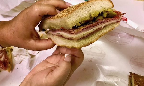 A woman's hands holding a Muffaletta slice at Central Grocery