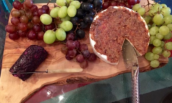 Cheeses and green grapes on a wood board