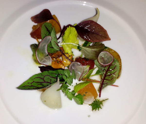 A white plate topped with colorful salad greens, pear and brittle