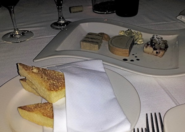 A white tablecloth topped with plates of Focaccia and Foie Gras Three Ways