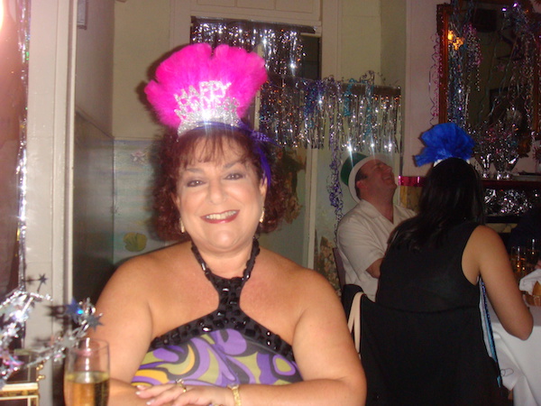 woman with dark hair wearing a feather Happy New Year tiara and festive shoulder baring blouse