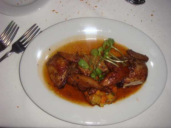 white shallow bowl filled with quail, vegetables, foie gras and pan gravy