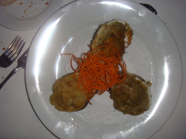 white plate with 3 baked oysters and shredded carrot garnish in center 