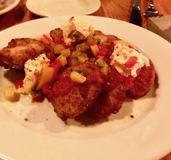 A white plate topped with fried tomato slices, cheese and red sauce
