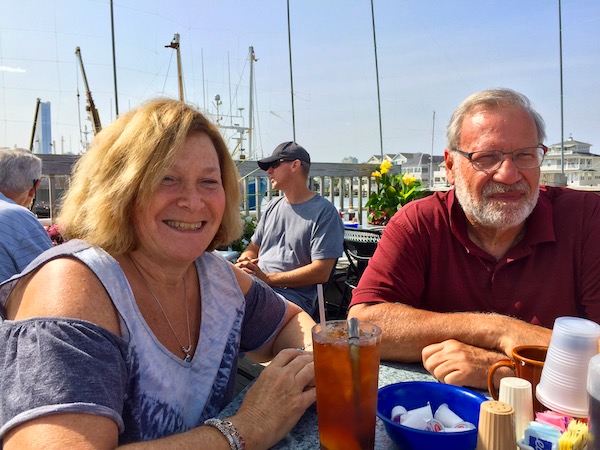 A man and a woman sitting at a table at a marina restaurant