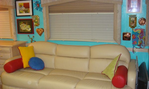 An RV living room with ivory leather sofa and turquoise walls