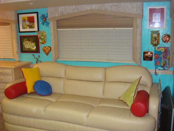 An RV living room with ivory leather sofa and turquoise walls