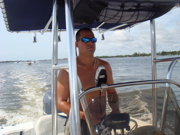 A young man with sunglasses steering a speed boat