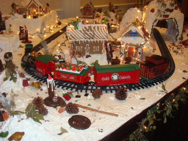 Large table display of miniature trains and gingerbread houses