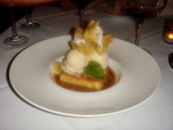 Large white plate with small deep well in center holding vanilla ice cream, bananas, French Toast and crisp slices of ripe plantains