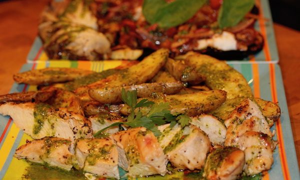 Multi colored striped plate with slices of grilled chicken in foreground and grilled fingerling potato halves behind, followed by grilled radicchio and eggplant slices