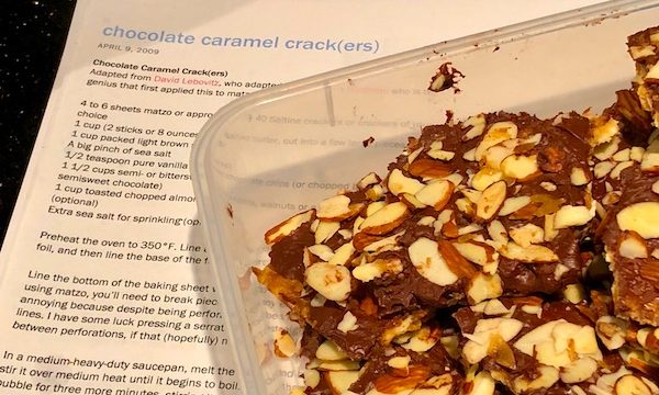 Caramel, Chocolate and Almond Covered Matzo in a plastic container sitting on top of the recipe