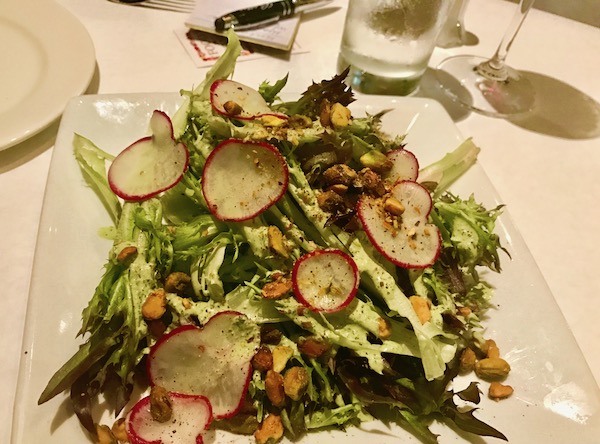 A white plate with a tumble of lettuces and sliced radishes
